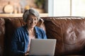 Smiling elderly woman in glasses using laptop at home Royalty Free Stock Photo