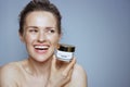 Happy modern woman with cosmetic cream jar on blue Royalty Free Stock Photo