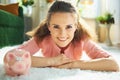 Happy modern woman with piggy bank at modern home in sunny day