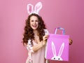 Happy modern woman on pink showing Easter shopping bag