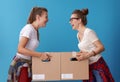 Happy women with cardboard boxes looking at each other on blue