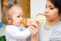 Happy mom and baby girl drinking from bottle. The concept of childhood and family. Beautiful Mother and her baby Royalty Free Stock Photo