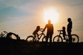 Happy mom, dad with kids biking at sunset
