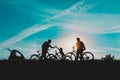 Happy mom, dad with kids biking at sunset nature