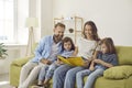 Happy mom, dad and kids looking through their family photo album or reading a book Royalty Free Stock Photo