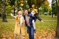 Happy mom, dad and son having fun together in the autumn park, throwing golden leaves and laughing Royalty Free Stock Photo