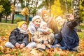 Happy mom, dad and sons playing having fun together, taking selfie on the mobile phone at the autumn park Royalty Free Stock Photo