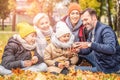 Happy mom, dad and sons playing having fun together, watching some funny things on the mobile phone at the autumn park Royalty Free Stock Photo