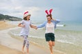 Happy mom and daughter child in Santa hat running along the beach Royalty Free Stock Photo