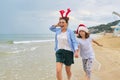 Happy mom and daughter child in Santa hat running along the beach Royalty Free Stock Photo