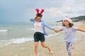 Happy mom and daughter child in Santa hat running along the beach Royalty Free Stock Photo