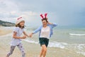 Happy mom and daughter child in Santa hat running along the beach Royalty Free Stock Photo