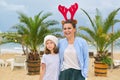 Happy mom and daughter child in Santa hat walking along beach Royalty Free Stock Photo