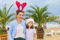 Happy mom and daughter child in Santa hat walking along beach Royalty Free Stock Photo