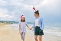 Happy mom and daughter child in Santa hat walking along beach Royalty Free Stock Photo