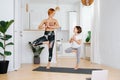 Happy mom and daughter doing yoga on a yoga mat, smiling at each other
