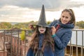 Happy mom and daughter get ready for halloween. cute witch with long curly hair posing in the photo next to her mother. Happy