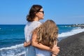 Happy mom and daughter kid hugging walking together along the beach, back view Royalty Free Stock Photo