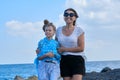 Happy mom and daughter kid hugging walking together along the beach Royalty Free Stock Photo