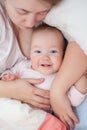 Happy mom and daughter lie on their backs. Happy smiling baby lying on bed at home. Beautiful smiling girl with blue eyes. Top Royalty Free Stock Photo