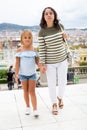 Happy mom and daughter walk along the street of European summer city