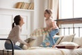 Happy mom and child girl enjoy pillow fight on bed