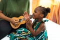 Happy Mom with her daughter playing guitar and singing together at home, happy family Royalty Free Stock Photo