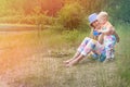 Happy mom and her little baby are playing by the lake in a summer green forest