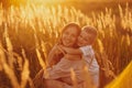 Happy Mom with Her Little Son Enjoying Summer Weekend Outside the City in the Field at Sunny Day Sunset. Young mother playing, Royalty Free Stock Photo