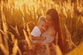 Happy Mom with Her Little Son Enjoying Summer Weekend Outside the City in the Field at Sunny Day Sunset. Young mother playing, Royalty Free Stock Photo