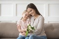 Happy mom hug little daughter thanking for presented flowers Royalty Free Stock Photo