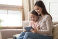 Happy mom and kid daughter using digital tablet on sofa Royalty Free Stock Photo