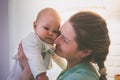 Happy mom kisses the cheek of an unhappy child holding him in her arms Royalty Free Stock Photo