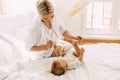Happy mom plays with her little son lying on the bed, mom and baby relax together. Innocence, unity and family Royalty Free Stock Photo