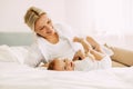 Happy mom plays with her little son lying on the bed, mom and baby relax together. Innocence, unity and family Royalty Free Stock Photo