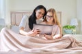 Happy mom and preteen daughter hugging together looking at screen of digital tablet Royalty Free Stock Photo