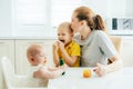 Happy mom spends time with the children in the kitchen feeding them.