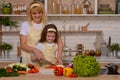 Happy mom teaches daughter to cook cut vegetables with a knife at home on the background of the kitchen. Happy pastime, Royalty Free Stock Photo