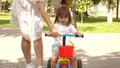 Happy mom teaches little daughter to ride a bike. mother is playing with child outdoors. child learns to ride bicycle Royalty Free Stock Photo