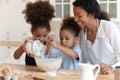 Happy mom teaching two preschooler kids to bake pie