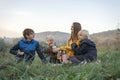 Happy mom and three kids have fun at picnic. Two boys and girl with mother drink hot drink on mountains background Royalty Free Stock Photo