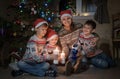 Happy mom and three sons with candles on the floor by the Christmas tree on Christmas day Royalty Free Stock Photo