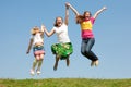 Happy Mom and two daughter jumping on green meadow Royalty Free Stock Photo