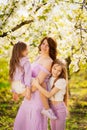 Happy mom and two daughters in a blossoming spring garden. parental love. Royalty Free Stock Photo