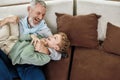 Happy moments. Portrait of cheerful grandfather and excited grandson embracing and having fun while relaxing on a couch Royalty Free Stock Photo