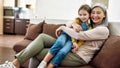 Happy moments. Portrait of cheerful grandmother and adorable granddaughter smiling at camera, embracing while sitting Royalty Free Stock Photo