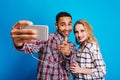 Happy moments together of excited lovely couple having fun on blue background. Making selfie portrait, cheerful mood Royalty Free Stock Photo