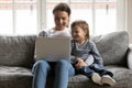 Smiling affectionate mum enjoying watching funny cartoons with small son.