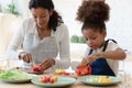 Happy mommy and cute daughter girl in aprons cooking together