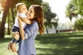 Happy mommy holding baby boy on the hands in the park with blurred background